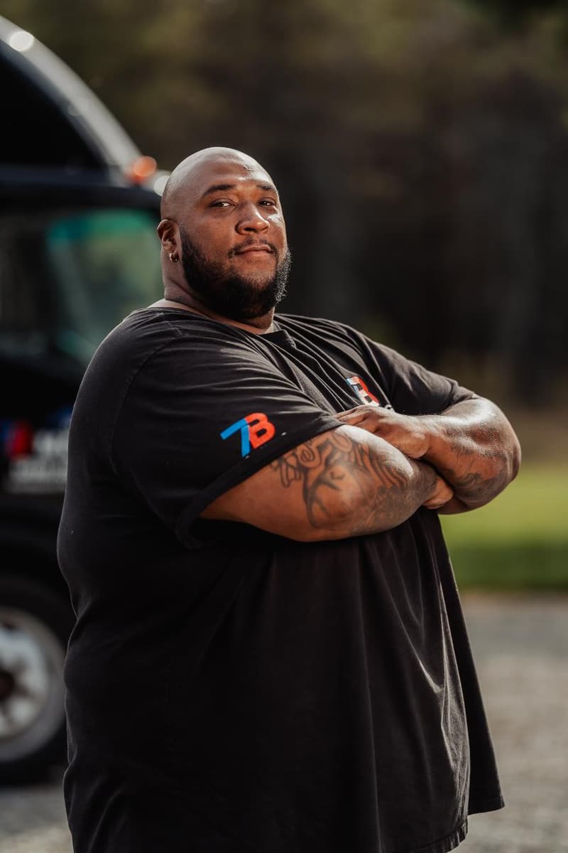 Maurice Luster standing with arms crossed in a black 7B Moving shirt in front of a box truck